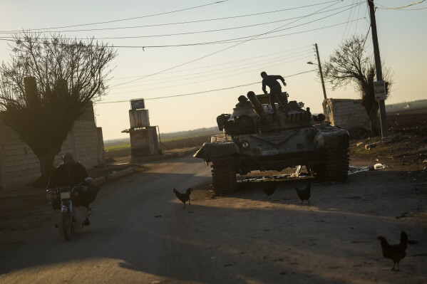 A child plays on top of an ousted Syrian government forces tank that was left on a street at the entrance of the town of Tel Rifaat in the Aleppo region of northern Syria, Tuesday, Jan. 28, 2025. (AP Photo/Khalil Hamra)