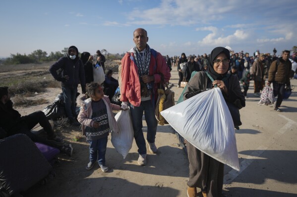 Ne'man Abu Jarad, center, and his wife Majida, center right, walk with their children as thousands of displaced Palestinians return to their homes in the northern Gaza Strip, following Israel's decision to allow them to go back for the first time since the early weeks of the 15-month war with Hamas, Monday, Jan. 27, 2025. (AP Photo/Abdel Kareem Hana)